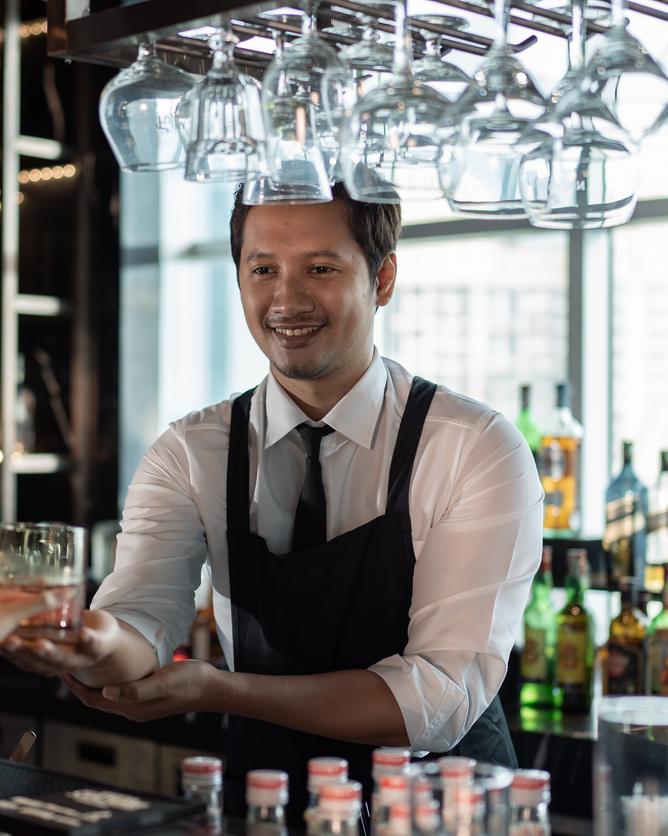 Barkeeper reicht einen Drink über den Tresen